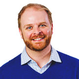 Cheerful man with short ginger hair and beard, in a bright blue sweater